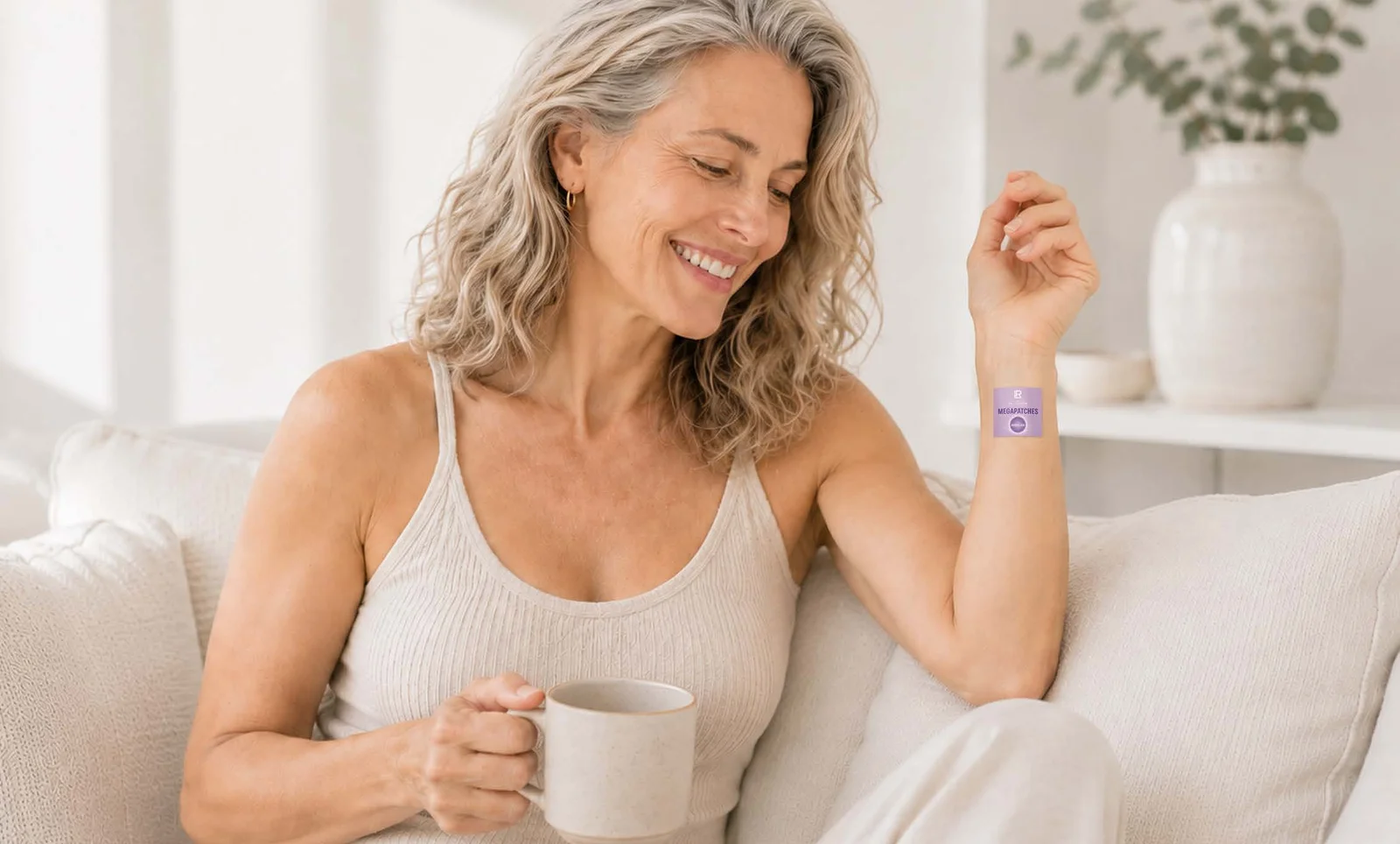 Frau mit Tasse auf dem Sofa, Patch am Oberarm – Wellness-Abend